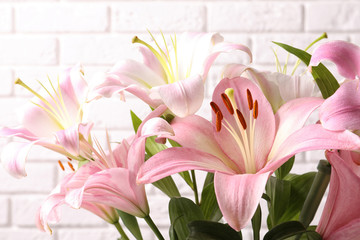 Fototapeta premium Beautiful blooming lily flowers on brick wall background