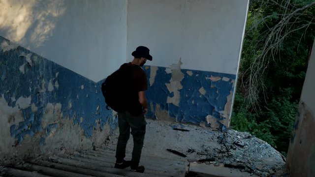 Tourist explores stairs of ruins of old building in apocalyptic world