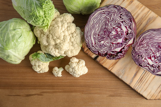 Flat lay composition with different cabbages on wooden background