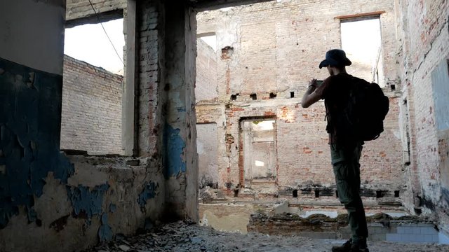 Tourist makes photos of ruins of building by mobile phone at his travel