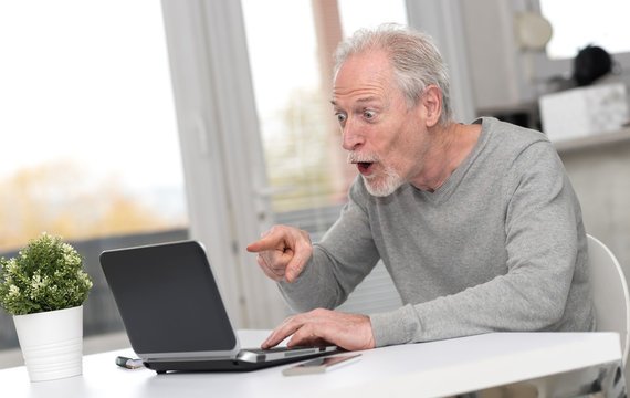 Happy mature man having a good surprise on laptop