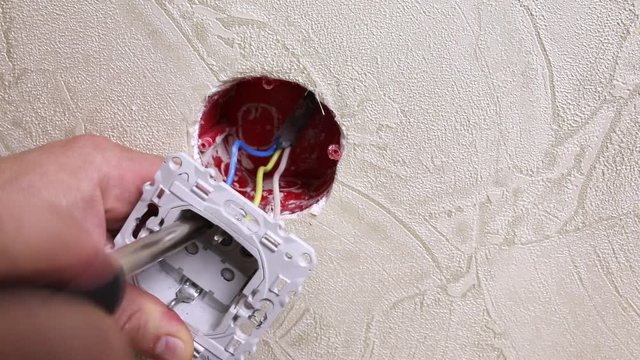 Male electrician puts on and repair an electrical outlet