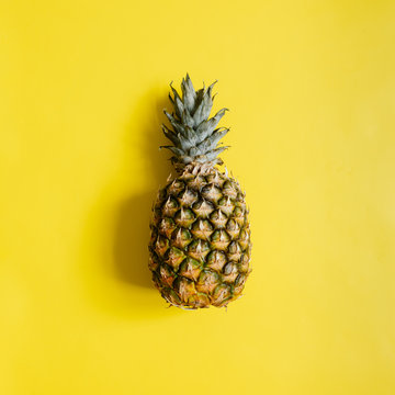 Ripe pineapple on vibrant yellow background isolated. Minimalist style trendy tropical concept. Room for text, copy, lettering.
