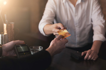 Man giving credit card to bartender in pub