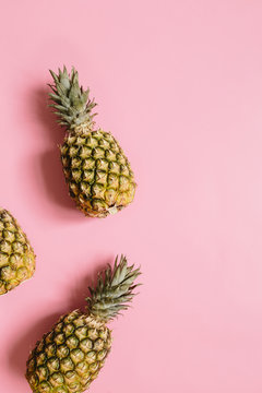 Tree ripe pineapples on faded rosy background isolated. Minimalist style trendy tropical concept.