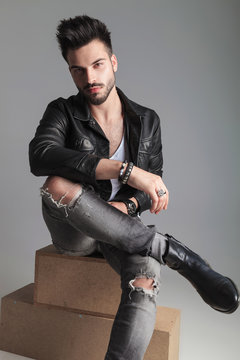 Handsome Man With Leather Jacket And Jeans Sitting Cross-legged