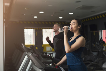 Fototapeta na wymiar Attractive woman on treadmill in fitness club