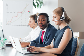Attractive young woman working in a call center with his colleagues