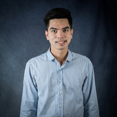 Obraz premium Portrait Handsome young asia man wearing a blue shirt doing smile and happiness isolated on black background. Businessman concept. Asia people.