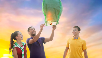 celebration and people concept - group happy friends lighting chinese sky lantern outdoors © Syda Productions