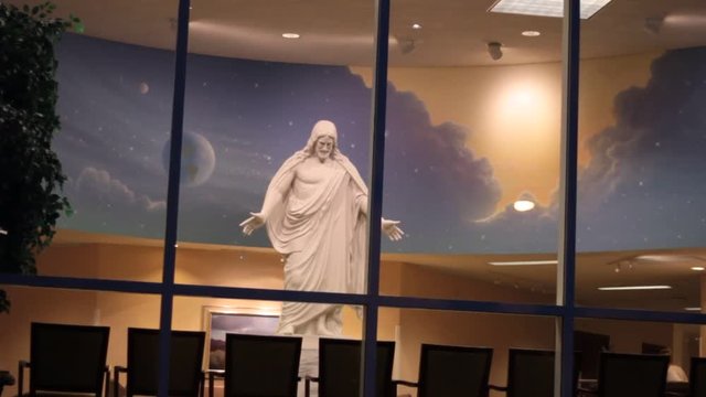 A large statue of Jesus Christ in a Place where people can sin inside on chairs and look at him.