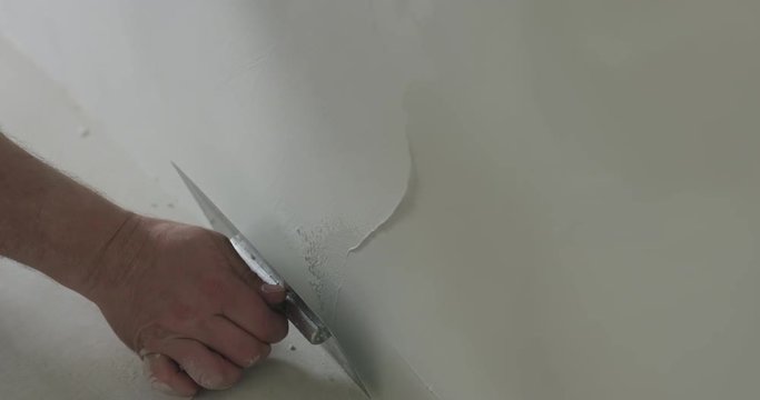 Slow motion handheld closeup worker applying decorative concrete plaster on the wall