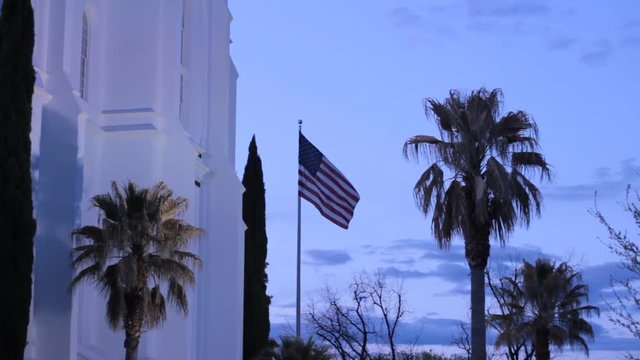 Flag Flying in a tropical hot place, Palm trees and lit up LDS temple.
