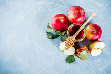 Jewish holiday Rosh Hashanah or apple feast day concept, with red apples, apple leaves and honey in jar, light blue background copy space above