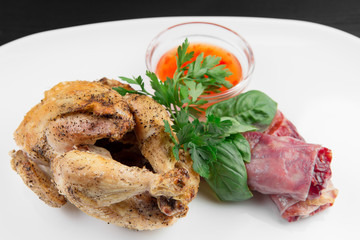 Roasted chicken on a white plate. Black wooden background.
