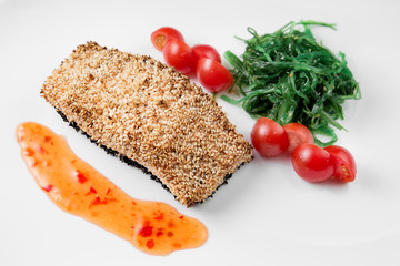 Grilled salmon with potatoes and sauce on white plate.