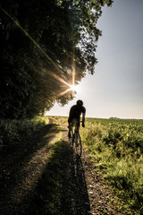 Rennradfaher im Sommer bei Sonnenuntergang