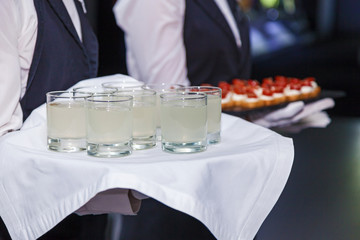 the waiter holds a tray with alcohol