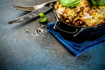 Traditional italian food, homemade lasagna with fresh basil, dark blue background copy space