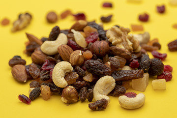 Mix of dried fruits and nuts on a yellow background