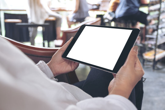 Mockup image of woman's hands holding black tablet pc with blank white desktop screen sitting in cafe