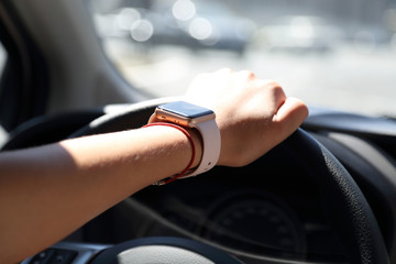 lady drives a car with one hand with a smart watch on it