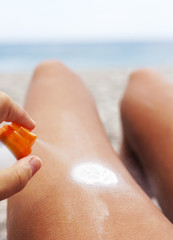 Spraying creme on body, summer beach and ocean,soft focus