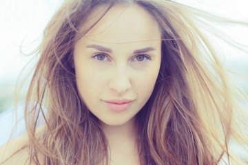 Naklejka premium Brunette beautiful disheveled hair portrait on the beach hairstyle