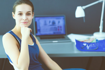 Young woman sitting at the desk with instruments, plan and laptop.