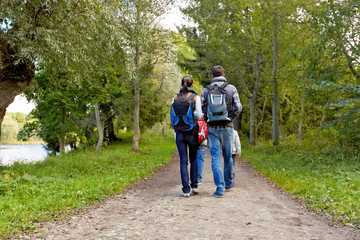 Obraz premium family, tourism and hiking concept - happy mother, father, son and daughter with backpacks walking in woods