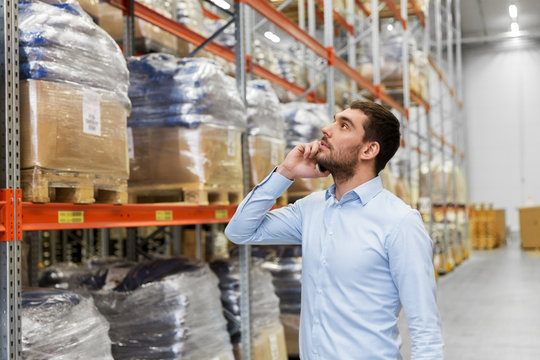 wholesale, logistic business, technology and people concept - businessman calling on smartphone at warehouse