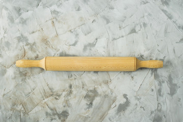 A wooden rolling pin for working with dough and baking on a gray table. Cooking tools concept. Top view, flat lay