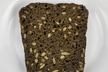 Black bread with seeds on a white plate.