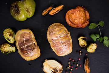 Meat products grilled and grilled vegetables on a dark background.