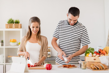 people and healthy eating concept - happy couple cooking food at home kitchen
