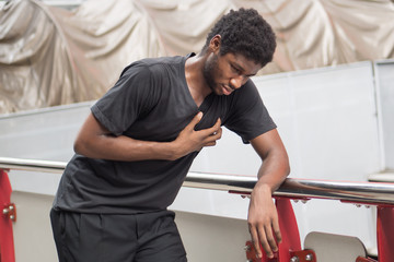sick african man with heart attack or chest pain; portrait of african man suffering from heart attack, chest pain, health care concept; young adult african man or black man model