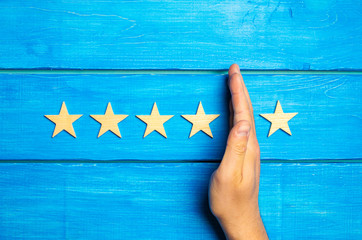 The hand divides the fifth star from the four others. Rating 5 stars, 4 stars. Overview of restaurant, hotel, cafe. The deterioration of the rating, the loss of the fifth star. Quality . Wooden stars