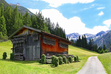 Holzhütte im Gebirge mit Holzpfählen zur Heutrocknung