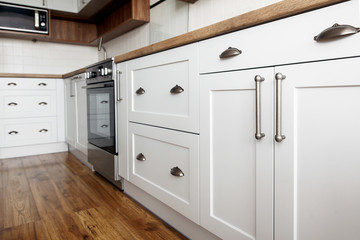 Stylish light gray handles on cabinets close-up, kitchen interior with modern furniture and...