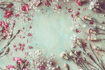 Summer flowers frame composition made with various colorful pastel garden flowers, petals and leaves on desktop background, top view. Retro styled