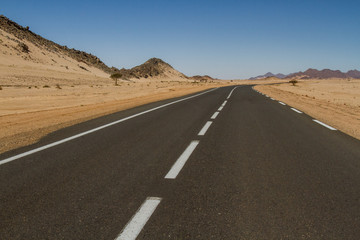 Empty straight and long road in the Sahara Desert, South Algeria, Africa