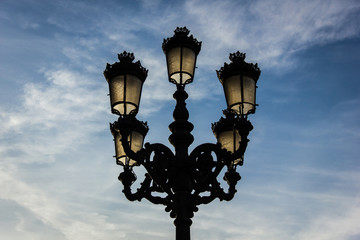Fototapeta na wymiar Traditional street lamp post over cloudy blue sky background in Bilbao city, north Spain. Electric company concept