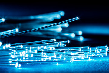 Bundle of optical fibers with lights in the ends. Blue background.