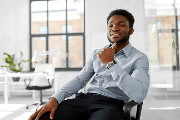 business and people concept - smiling african american businessman sitting on office chair