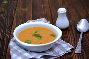 Popular Israeli orange soup cream with pumpkin, carrots, sweet potato and red lentils on a wooden background