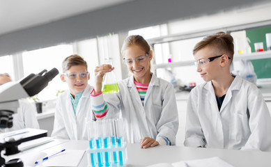 education, science and children concept - kids with test tubes studying chemistry at school...