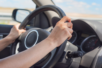 Female hands on the steering wheel of a car while driving