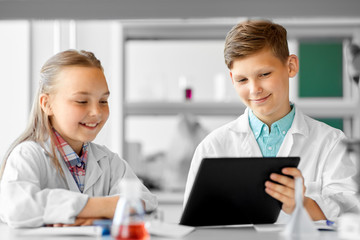 Fototapeta premium education, science and technology concept - kids with tablet pc computer studying chemistry at school laboratory