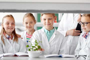 education, science and school concept - kids or students and teacher with plant at biology class