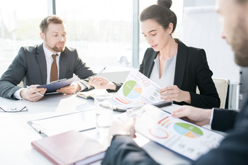 Fototapeta premium Portrait of beautiful young businesswoman heading meeting sitting at meeting table in conference room and reading marketing reports, copy space